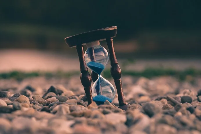 An hourglass sitting on top of sand slowly counting time.